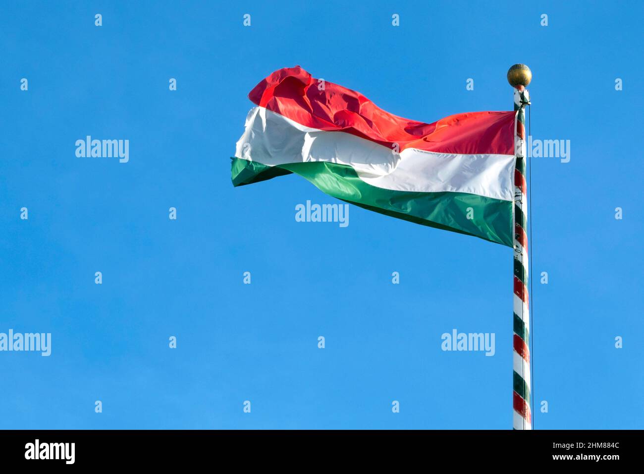 Ungarische Flagge oder Flagge Ungarns winkt gegen blauen Himmel, Platz für Text Stockfoto