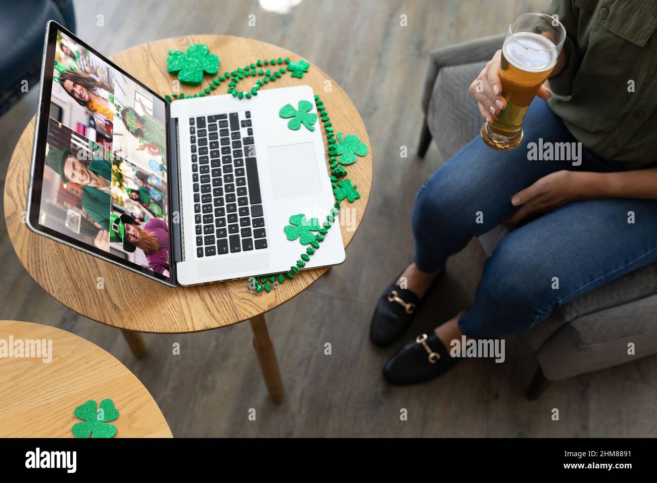 Eine mittlere Frau, die Bier hält, während sie an einer Bar eine Videokonferenz auf einem Laptop veranstaltet Stockfoto