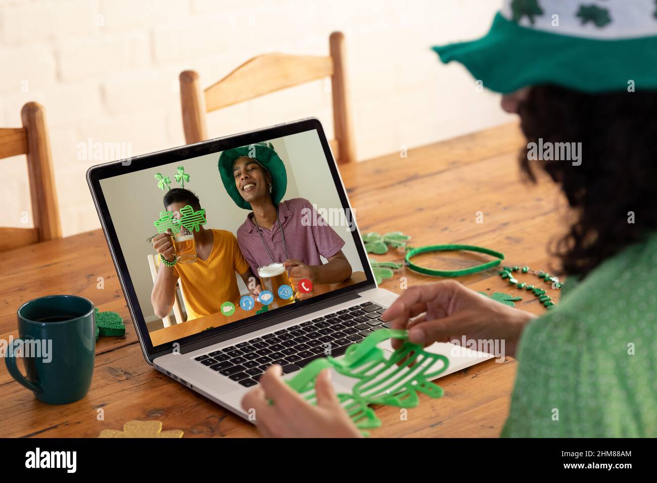 Kaukasische Frau, die eine Schamrock-Brille hält, während sie zu Hause einen Videoanruf auf dem Laptop führt Stockfoto