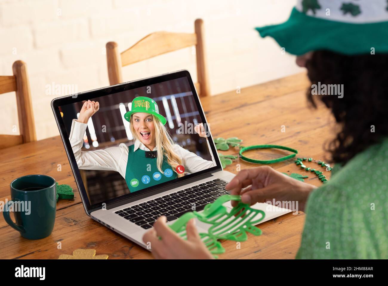 Kaukasische Frau, die eine Schamrock-Brille hält, während sie zu Hause einen Videoanruf auf dem Laptop führt Stockfoto