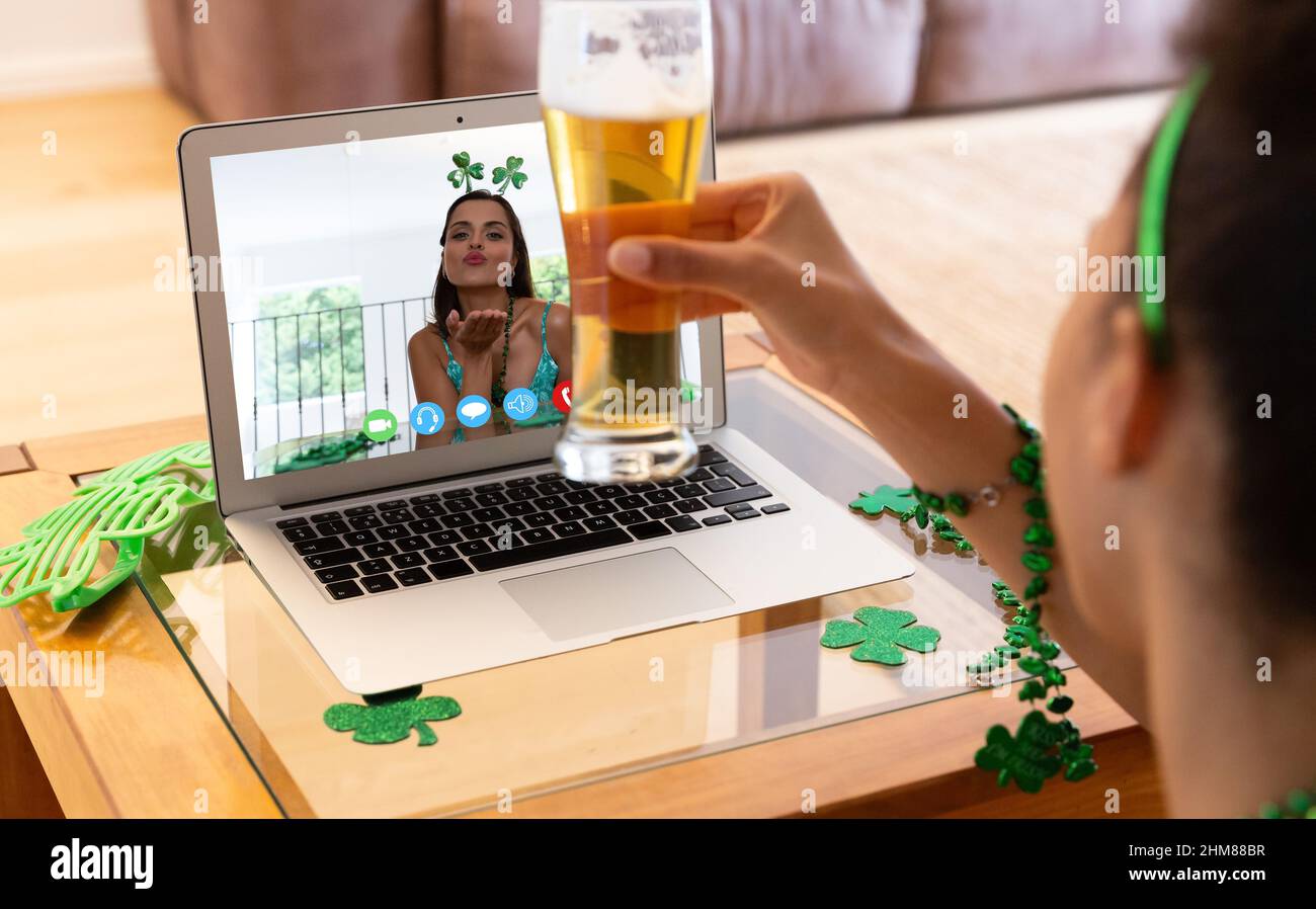 afroamerikanische Frau mit einem Bierglas und einem Videoanruf auf dem Laptop zu Hause Stockfoto