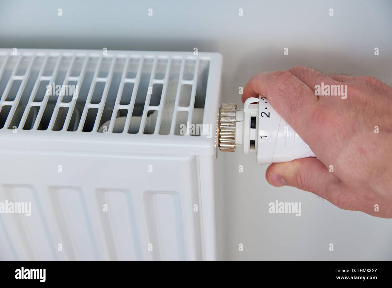 Die Temperatur am Heizkörper-Thermostat von Hand einstellen und den Heizkörper-Regler drehen, um die Wärme zu Hause zu steuern Stockfoto