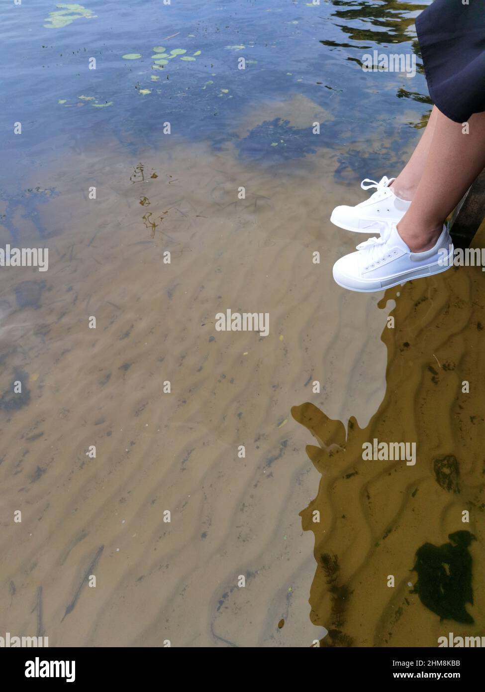 Frau Beine über dem Wasser auf einem Dock, Sommer relax Stockfoto
