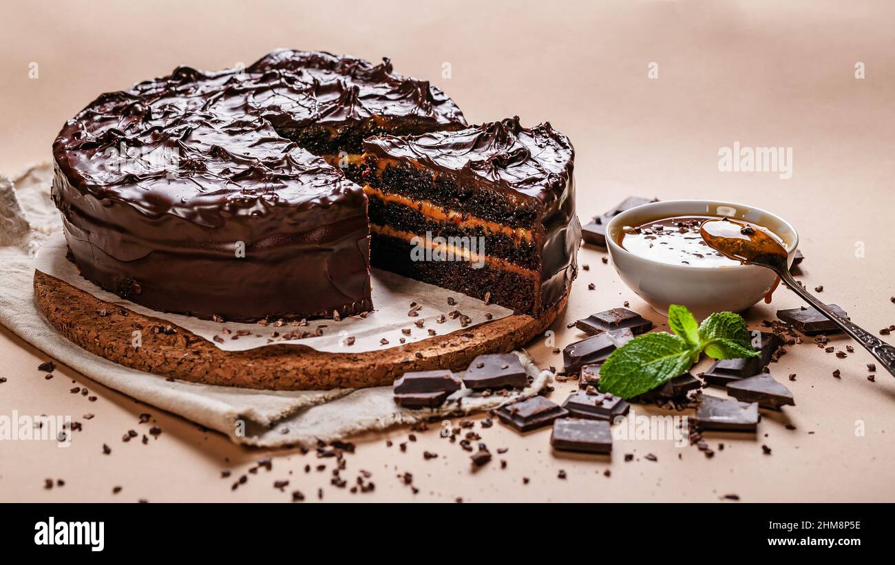 Lebensmittelbanner. Schokoladenkuchen mit gesalzenem Karamell auf beigefarbenem Hintergrund. Hausgemachtes, köstliches Gebäck. Süßes Dessert. Stockfoto