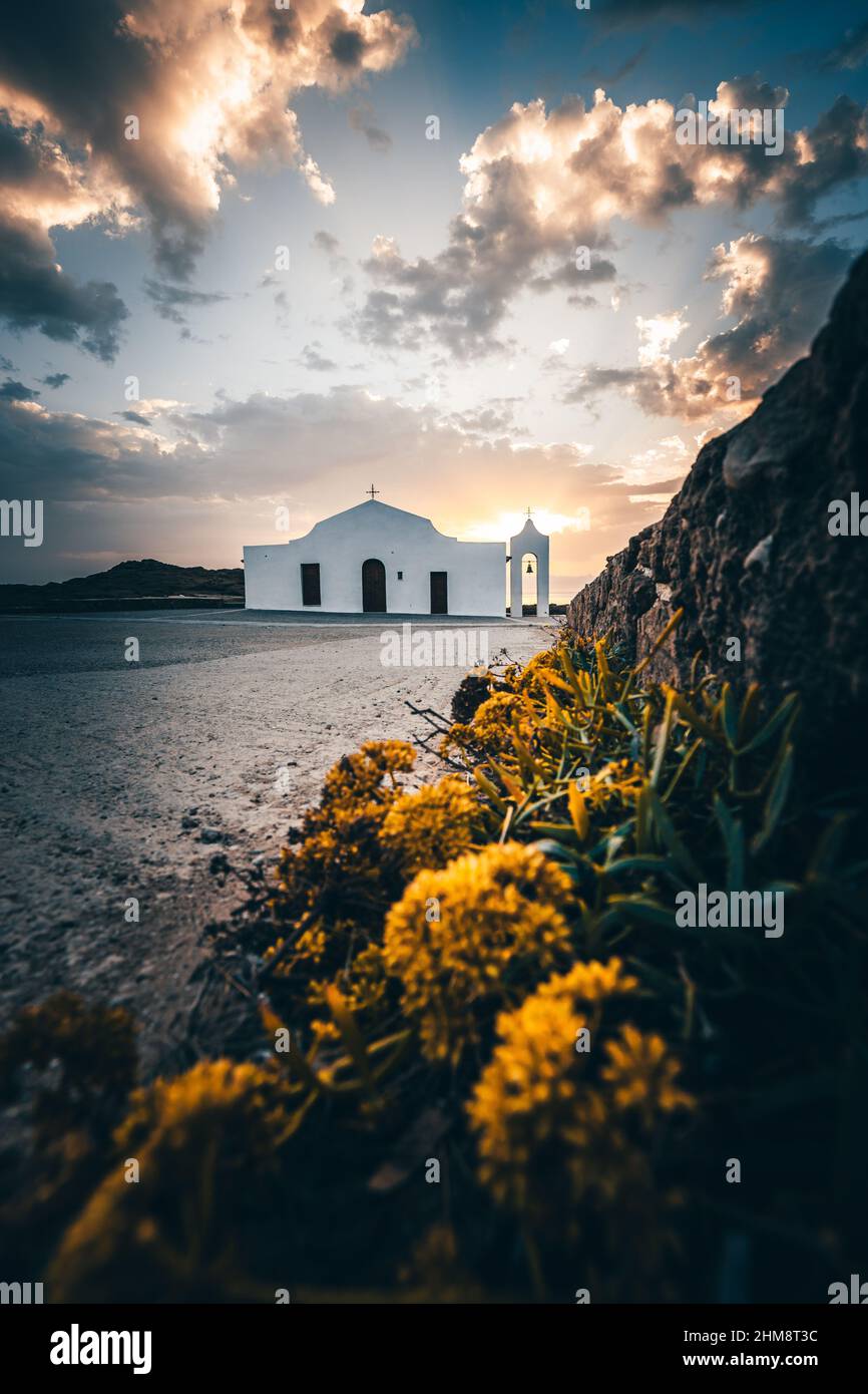 Die Kirche von Agios Nikolaos auf Zakyntos, am Strand von St. Nikolaus, Sonnenaufgang direkt am Meer. Landschaftsaufnahme der Kirche hinter der Kirche die Sonne Stockfoto