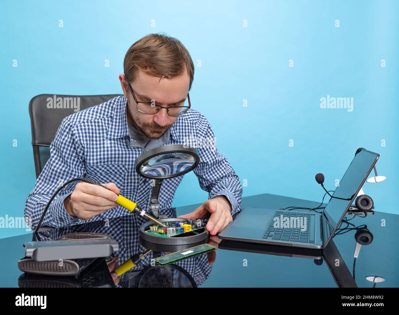 Potrait des professionellen Programmierers, des technischen Spezialisten, der mit dem Motherboard auf blauem Hintergrund isoliert arbeitet Stockfoto