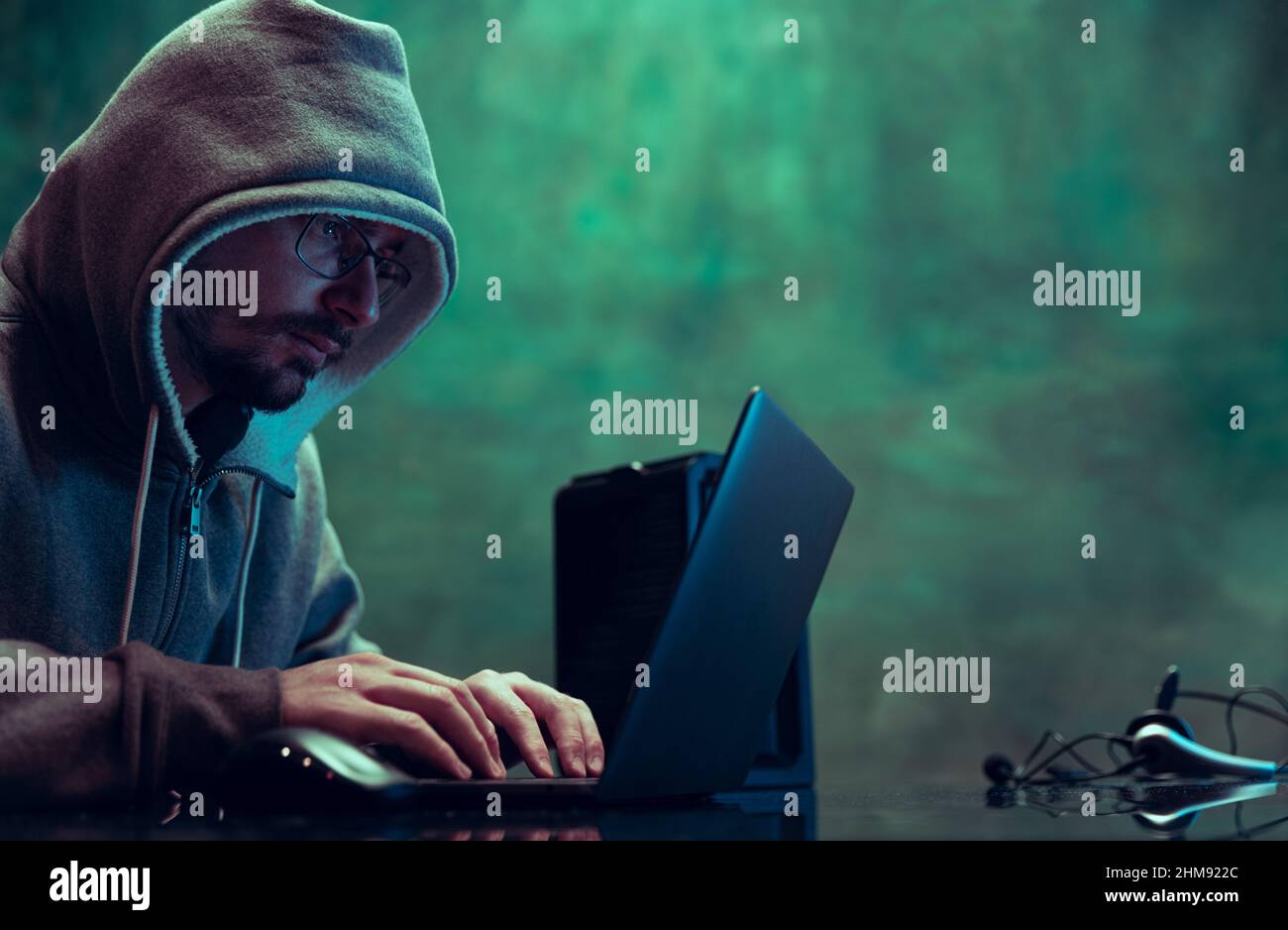 Porträt des Mannes, professionelle Programmierer, Web-Hacker brechen Sicherheitssystem, Herunterladen von Informationen isoliert über dunkelgrünen Hintergrund in Neon Stockfoto