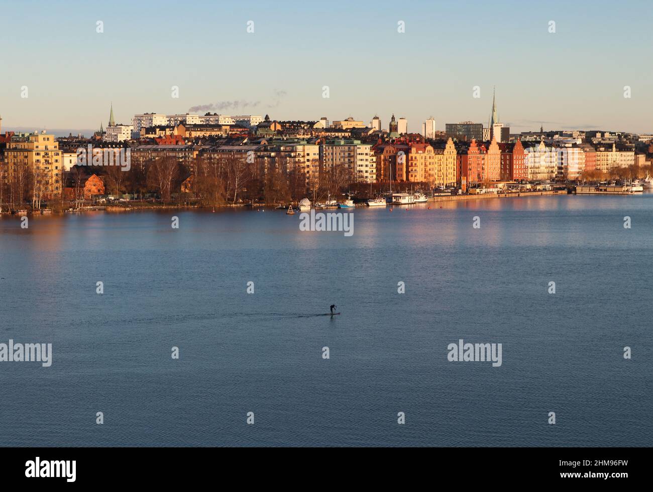 Einflügiger Paddelboarder, der bei Sonnenuntergang den Stockholmer Archipel durchquert, aufgenommen von der Westbrücke, Stockholm, Schweden. Hochwertige Fotos. Stockfoto