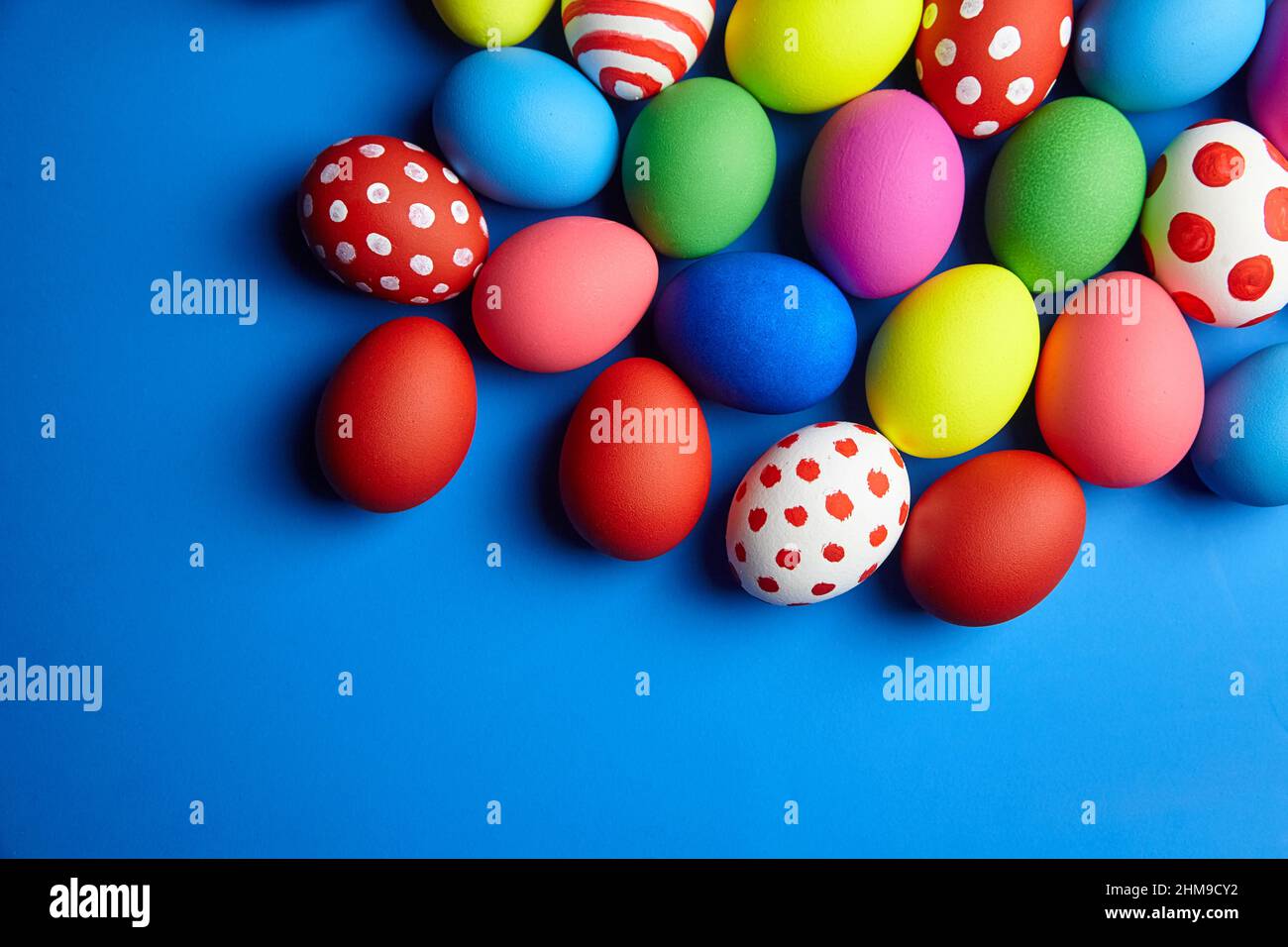 Ostersonntag oder Ostertag (Pascha). Farbenfrohe Ostereier auf blauem Hintergrund mit Platz zum Kopieren. Bemalte Hühnereier, Blick von oben Stockfoto