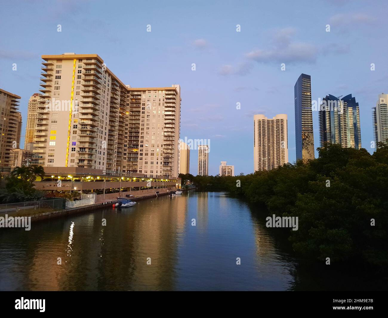 Sunny Isles, USA - 22. März 2021: Hochhäuser und grüne Bäume entlang des Flusses am blauen Himmel Stockfoto