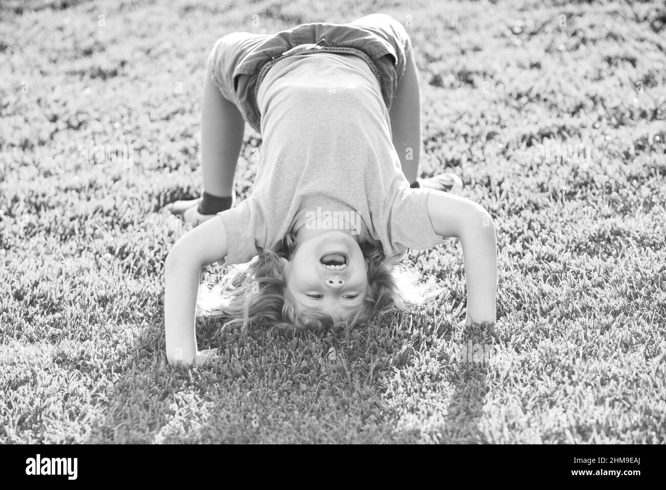 Glückliches Kind Junge Mädchen steht auf dem Kopf auf Gras im Sommer Tag. Stockfoto