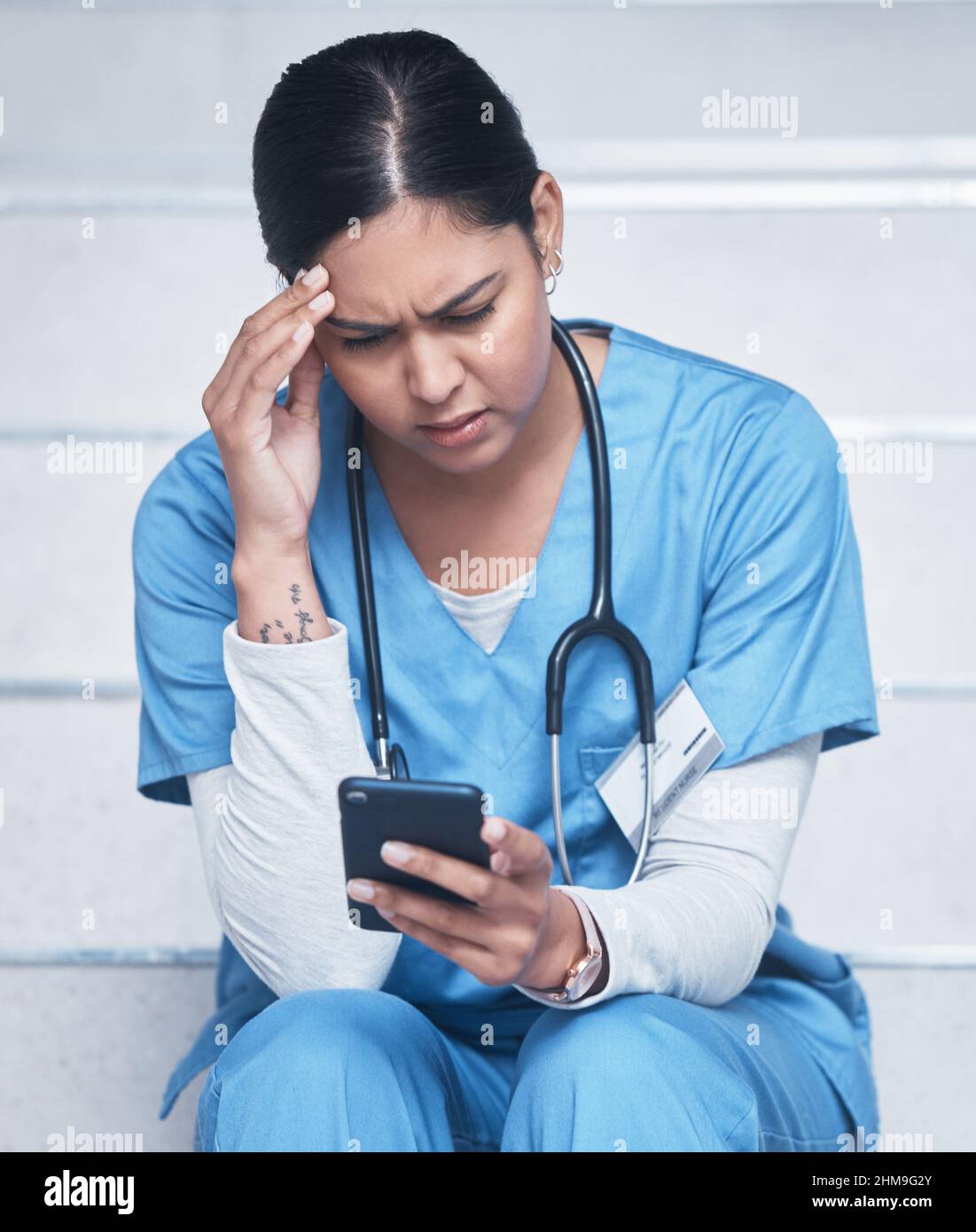 Es sieht so aus, als ob ich für eine andere Schicht gebucht hätte. Aufnahme einer Krankenschwester, die beim Benutzen ihres Mobiltelefons aufgeregt aussugt. Stockfoto