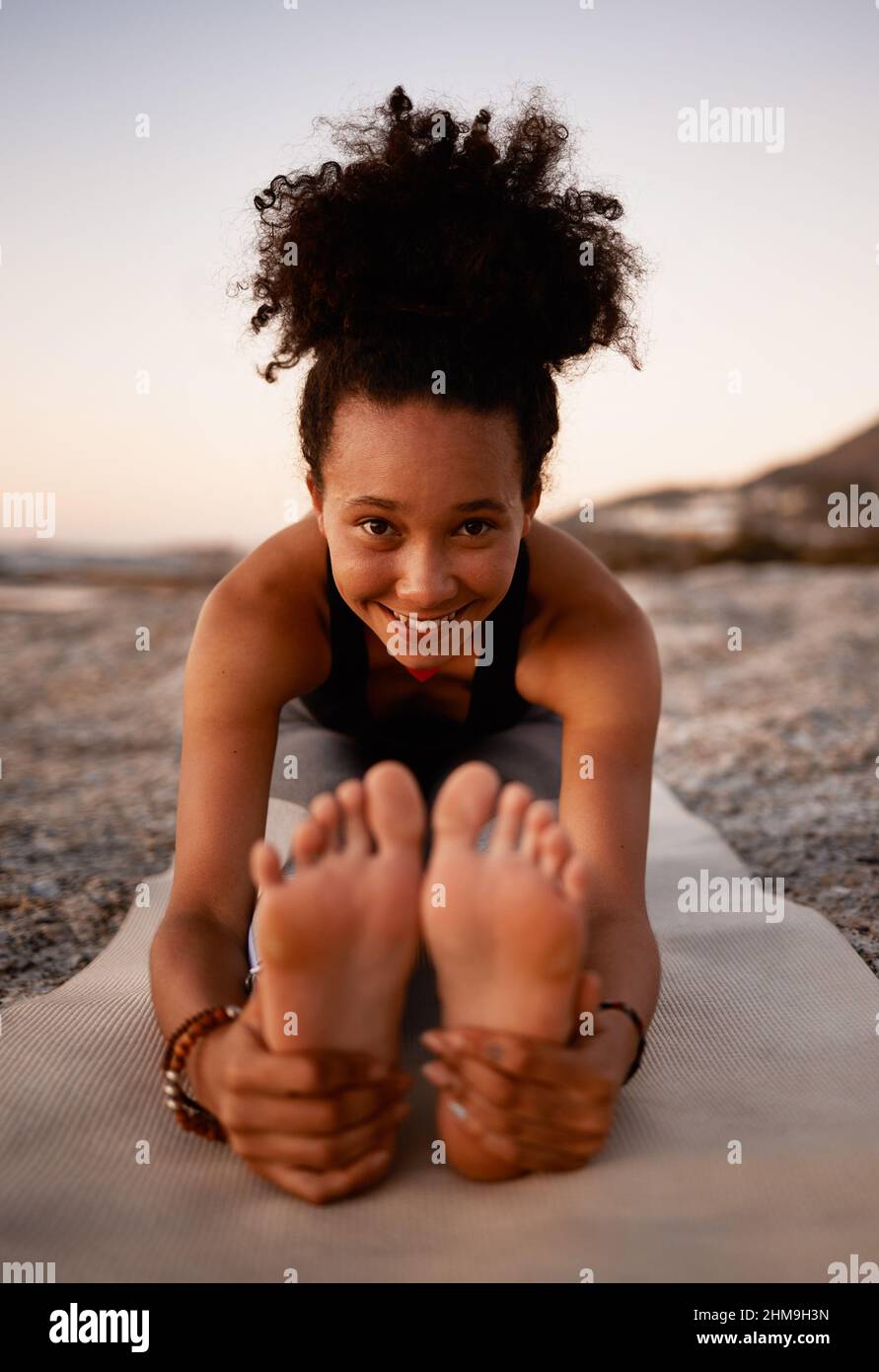 Man muss limber bleiben. Ganzkörperportrait einer attraktiven jungen Frau, die am Strand bei Sonnenuntergang Yoga praktiziert. Stockfoto