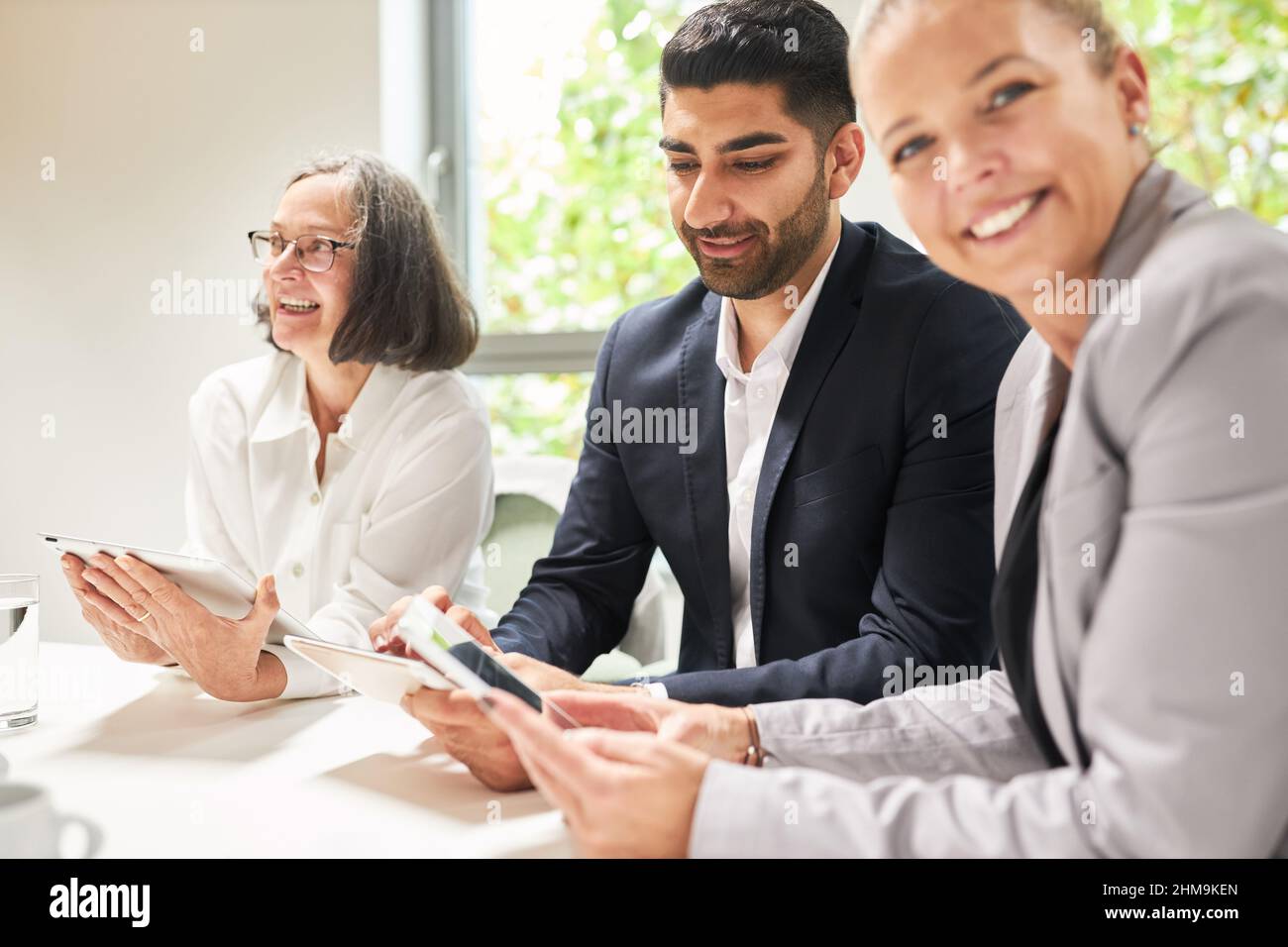In der Computerwerkstatt im Büro arbeiten drei Geschäftsleute mit Tablet-Computern zusammen Stockfoto