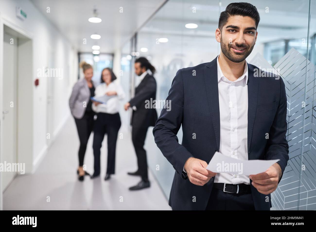 Junger Geschäftsmann als Bewerber oder Auszubildender freut sich über den Arbeitsvertrag im Flur im Büro Stockfoto