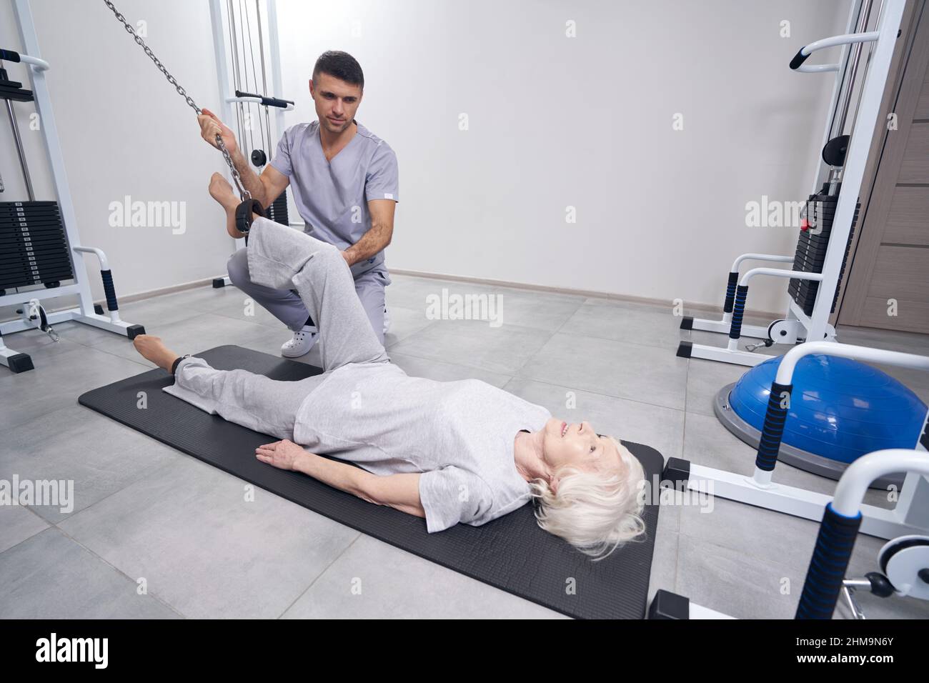 Ältere Frau trainiert Beine mit Kabelmaschine Stockfoto