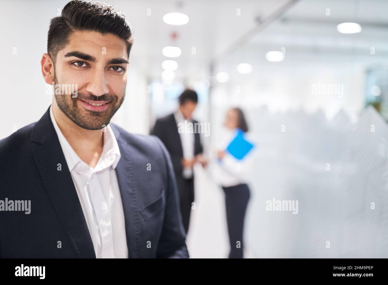 Lächelnder junger Geschäftsmann als Auszubildender oder erfolgreicher Manager auf dem Flur vom Büro aus Stockfoto