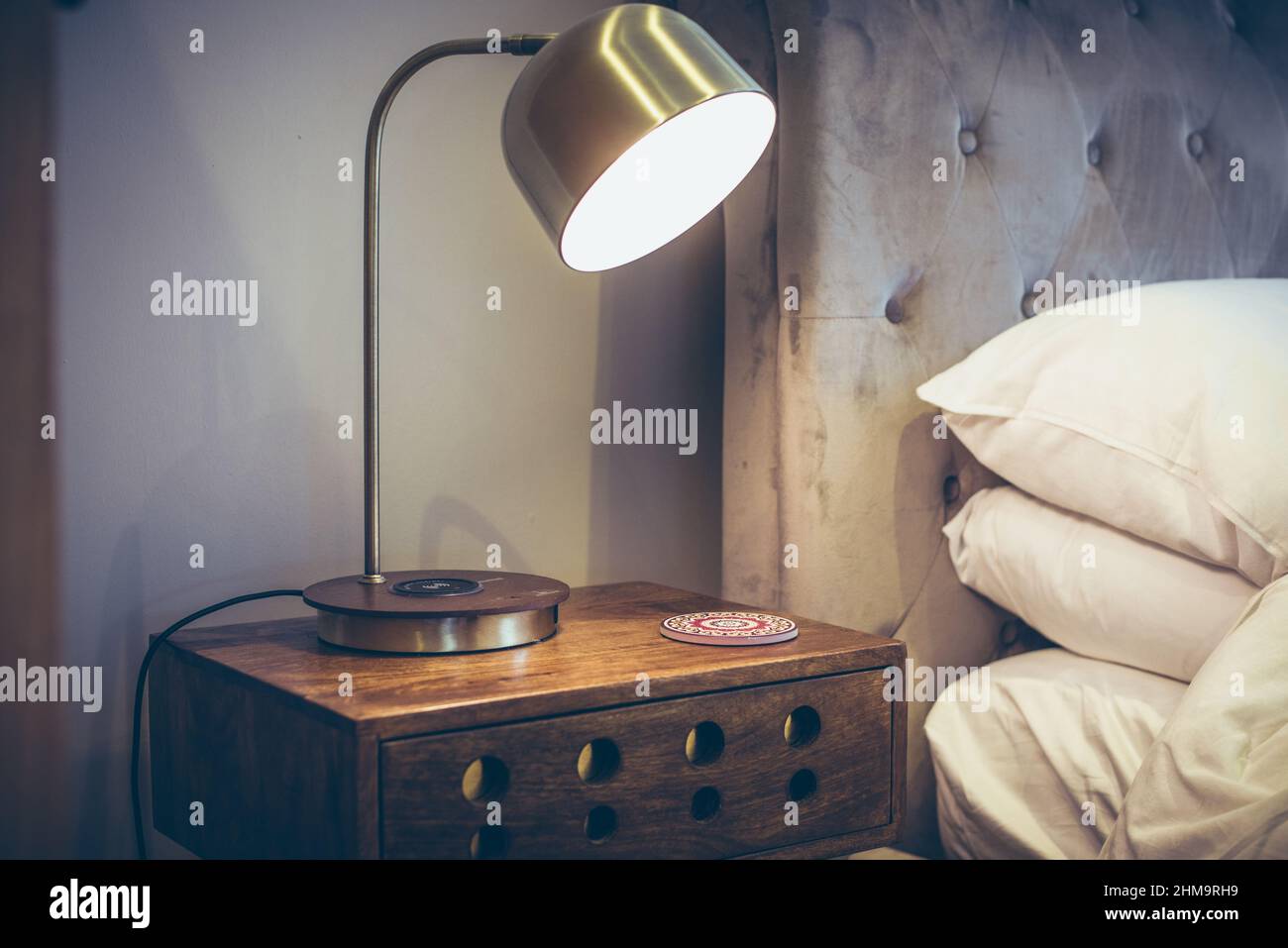 Lampe auf einem Vintage-Tisch neben einem Bett mit weichen Kissen in den Schlafzimmern Stockfoto