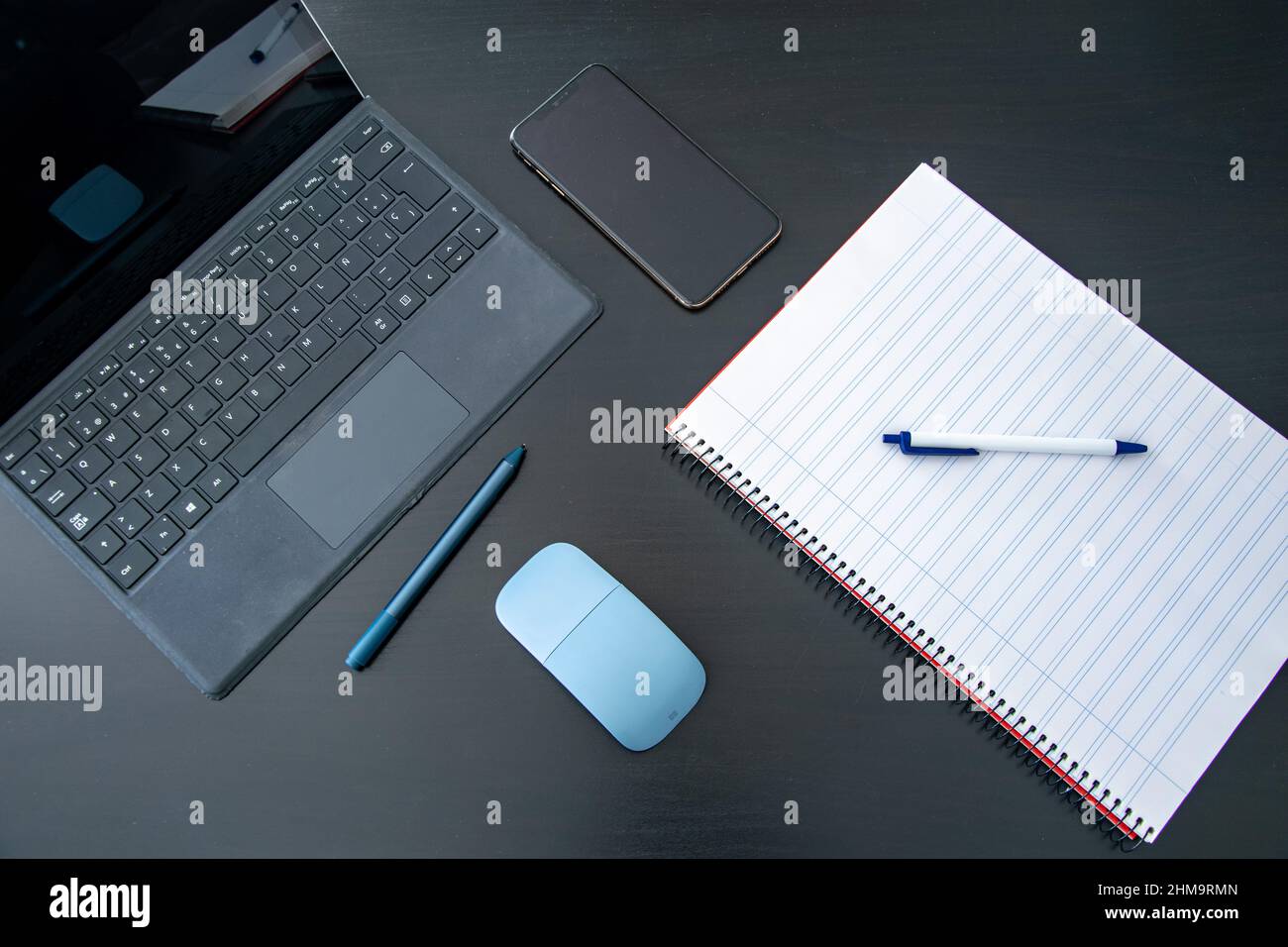 Ein Bild von einem Laptop-Tablet und einem Notizblock mit einem Stift auf einem schwarzen Tisch, der zum Lernen oder Arbeiten von zu Hause bereit ist Stockfoto