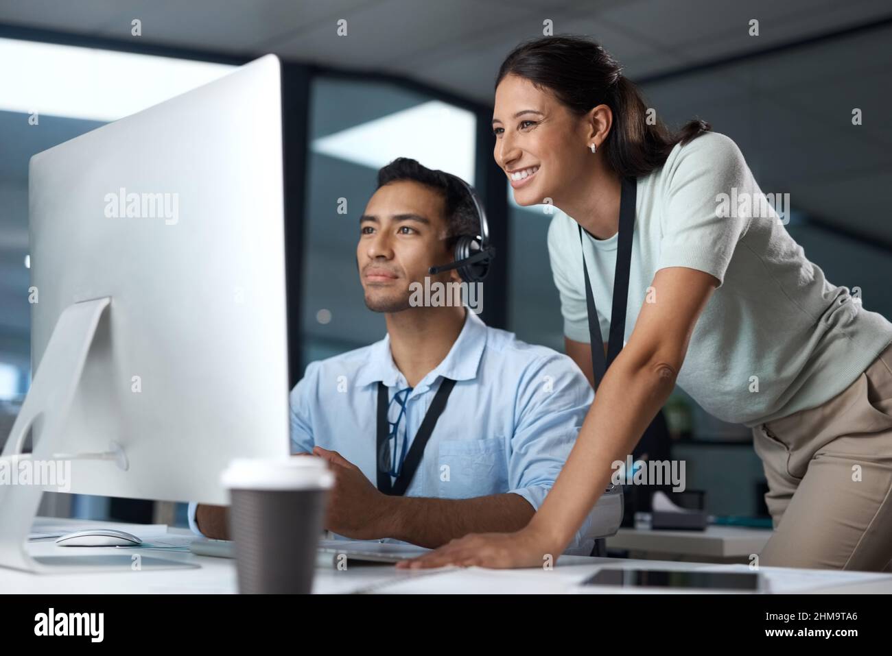 Weitergabe von sage-Kundenberatung. Aufnahme eines jungen Mannes und einer jungen Frau, die einen Computer benutzen, während sie in einem Callcenter arbeiten. Stockfoto