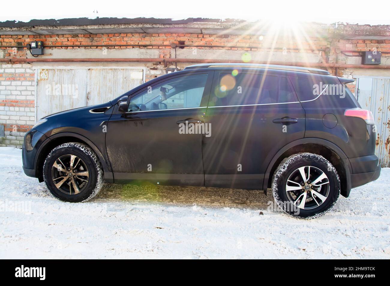 Auto Toyota Raw4 vor dem Hintergrund der Backstein-Garage und rostigen Metalltüren an einem sonnigen Wintermorgen. Stockfoto