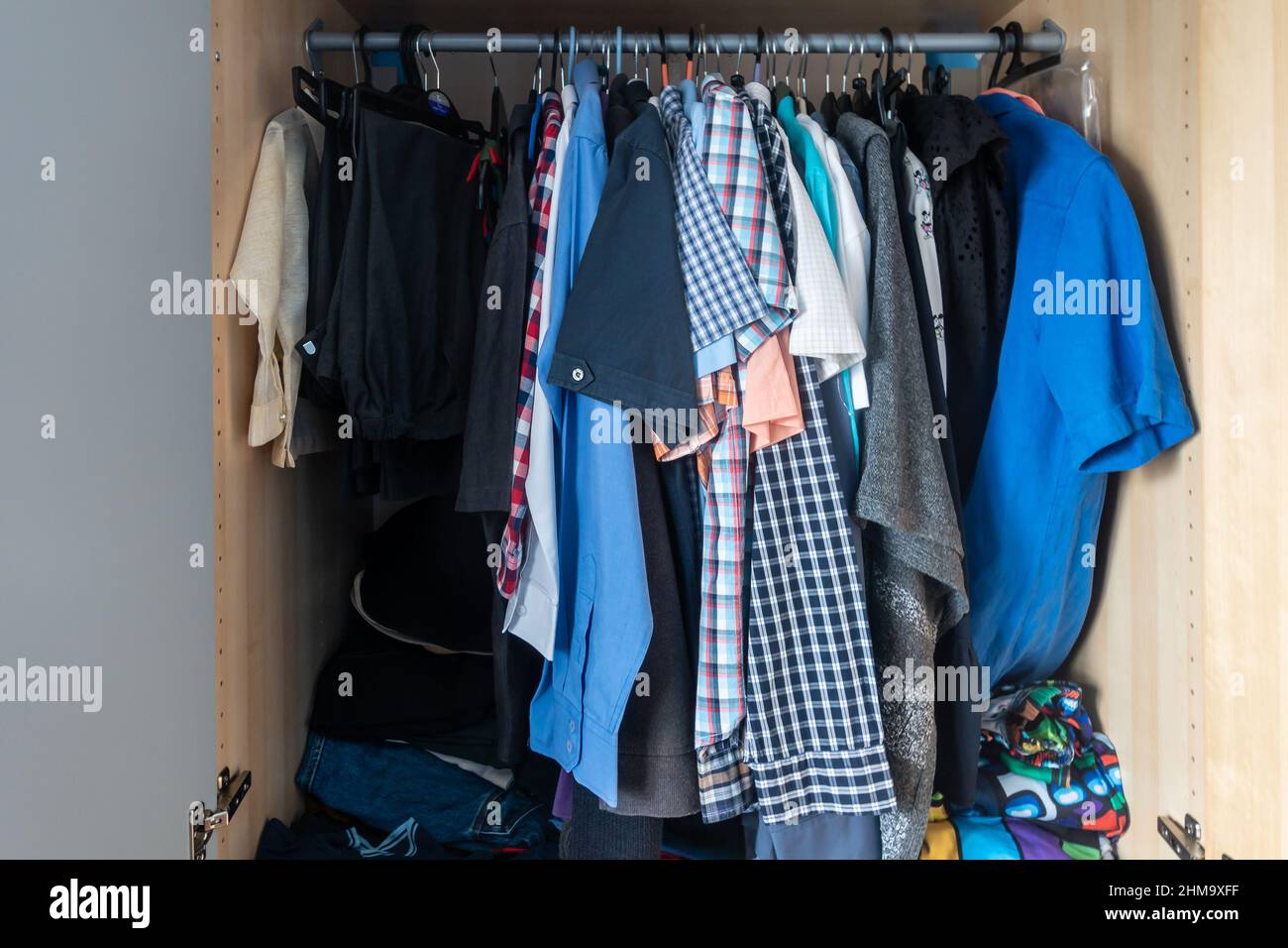 Kleidung, die an einem Kleiderständer in einem Kleiderschrank hängt. Stockfoto