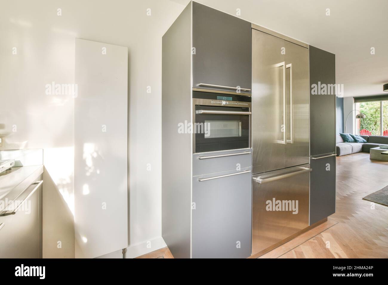 Moderner Einbauofen und Kühlschrank in der Nähe der Theke in der hellen  Küche mit modernen Geräten in einem geräumigen Apartment mit Couch zu Hause  platziert Stockfotografie - Alamy