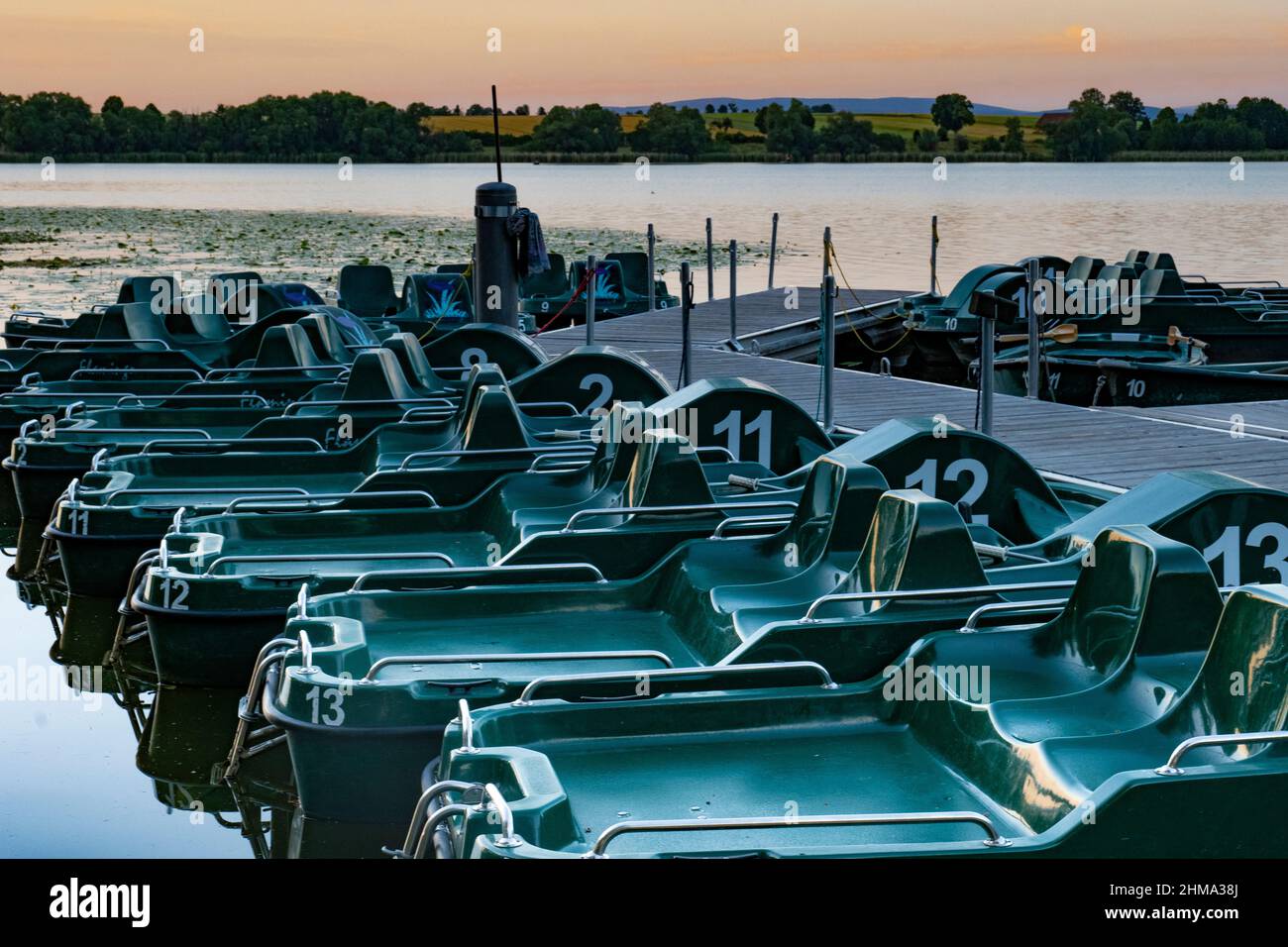 Eine Landestelle mit grünen Tretbooten bei Sonnenuntergang Stockfoto