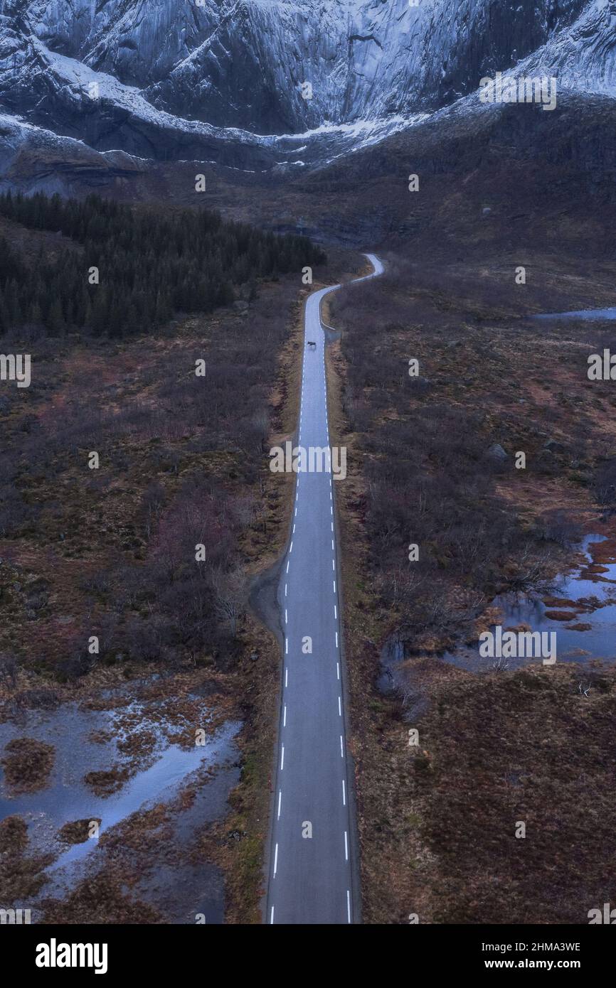 Drone Blick auf lange schmale Asphaltstraße mit Herstellung Linien zwischen Feuchtgebiet mit verdorrtem Gras in der Natur von Norwegen laufen Stockfoto