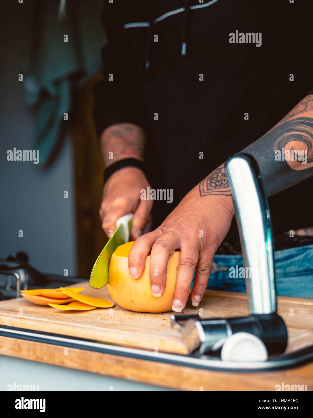 Crop anonyme weibliche schneiden frischen reifen Kürbis auf Holz Schneidebrett während der Vorbereitung Mittagessen in Wohnwagen während der Reise in Kantabrien Stockfoto