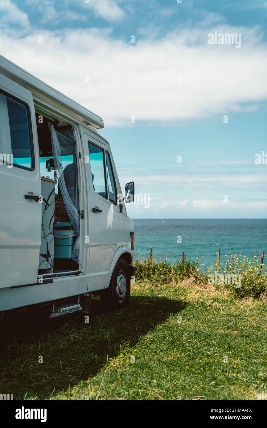 Wohnmobil für Autoreise geparkt an der grasbewachsenen Küste von türkisfarbenem Wasser des Meeres in Kantabrien gewaschen Stockfoto