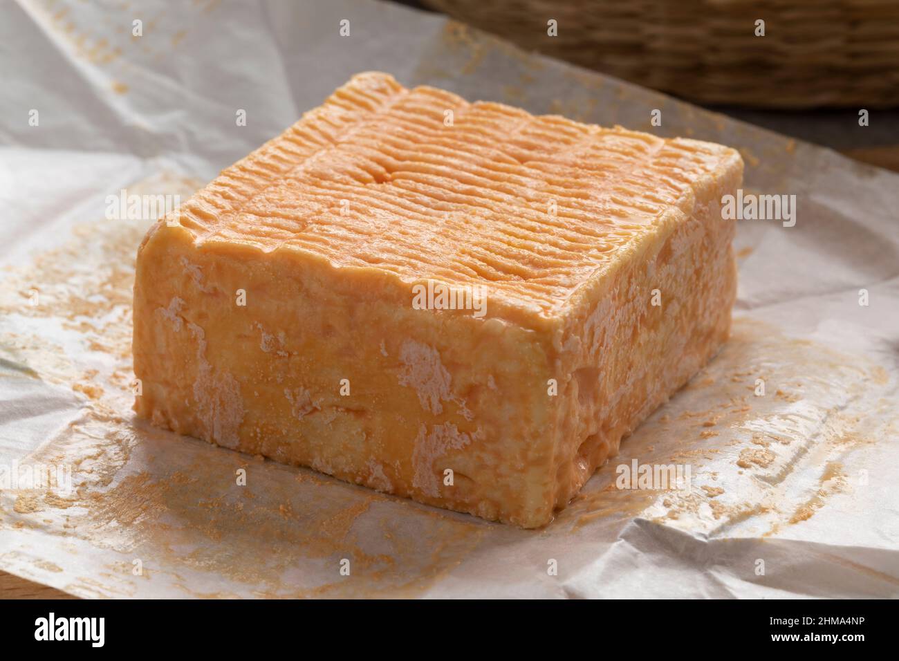 Einzelnes ganzes Stück Limburger oder Herve Käse mit starkem Geruch auf Packpapier Stockfoto