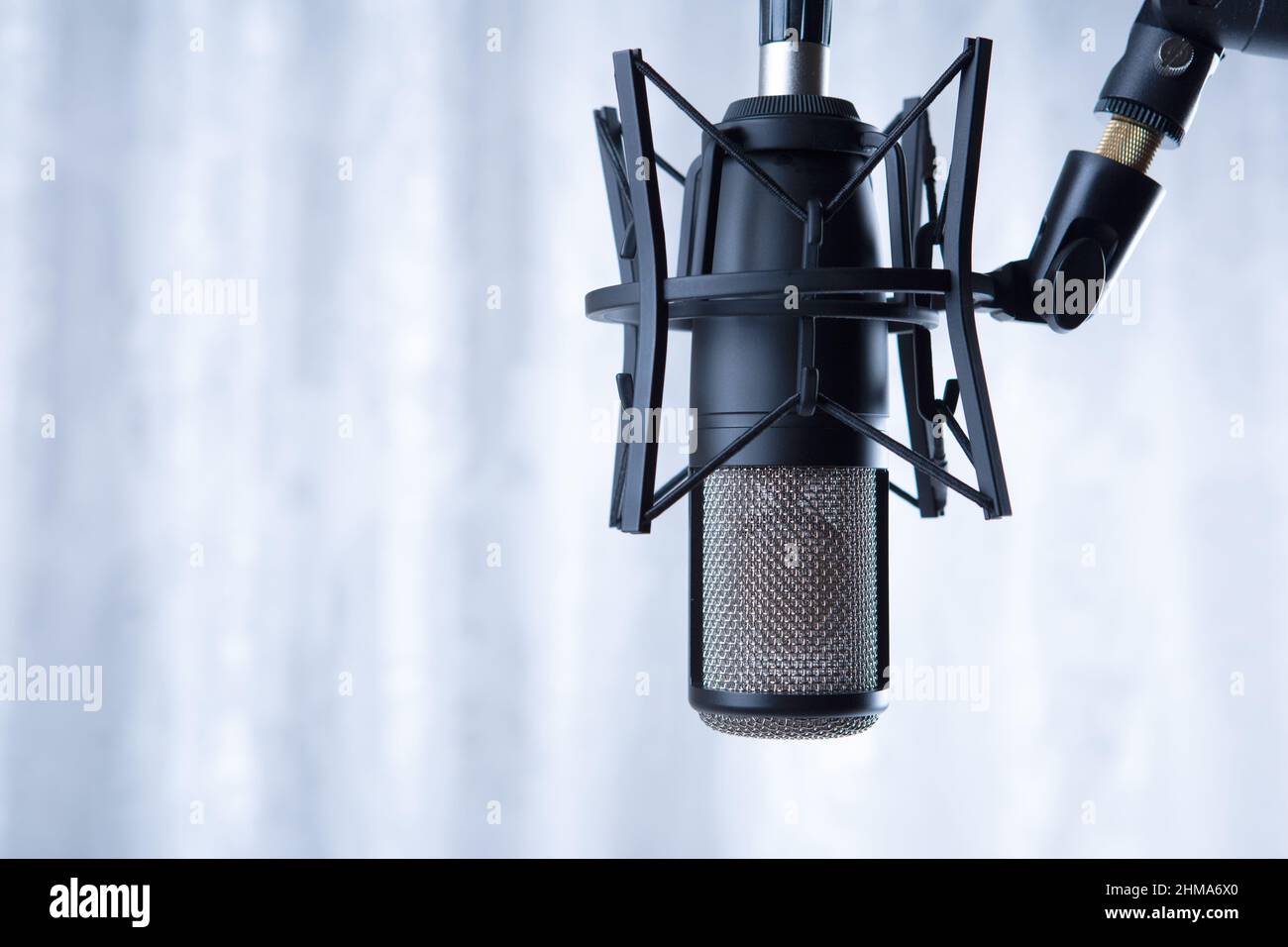 studio schwarzes Kondensatormikrofon gegen graue Vorhänge aus nächster Nähe Stockfoto