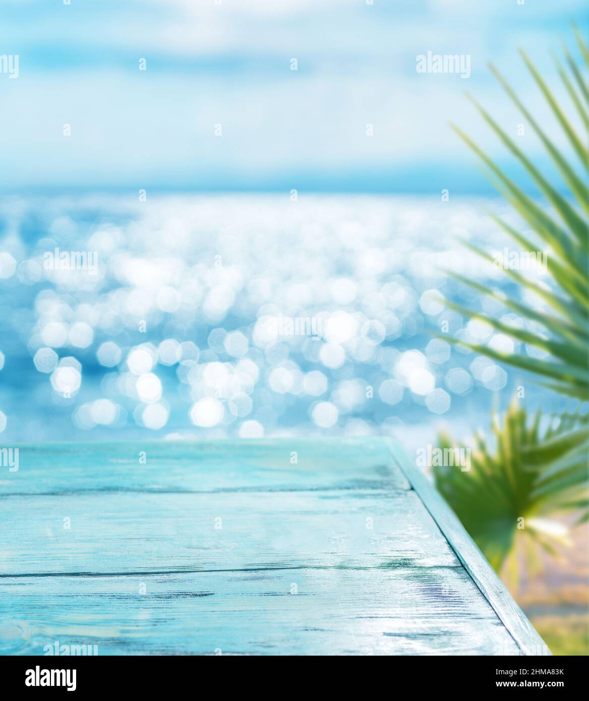 Blaues Holzbrett und verschwommenes glitzerndes Meer im Hintergrund. Es ist möglich, Ihr Produkt zu platzieren. Sommerferienkonzept. Stockfoto