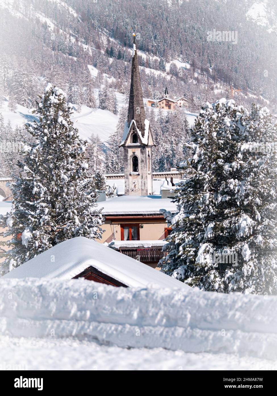 Cinuos-Chel, Schweiz - 3. Februar 2022: Winteransicht auf einem Glockenturm einer protestantisch reformierten Kirche in einem schneebedeckten Dorf von Cinuos Chel in eng Stockfoto