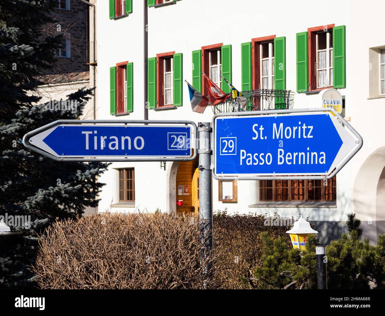 Poschiavo, Schweiz - 19. Januar 2022: Ein blaues schweizer Straßenschild, das die Richtung St.Moritz, Bernina-Pass und Tirano in Ita angibt Stockfoto