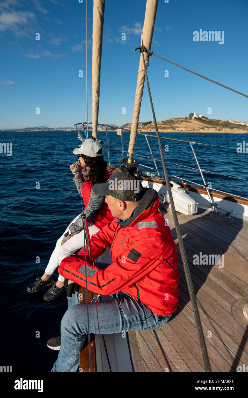 Junges erwachsenes Paar, das auf einem Segelboot auf der Bucht von Alicante, Costa Blanca, Spanien segelt Stockfoto