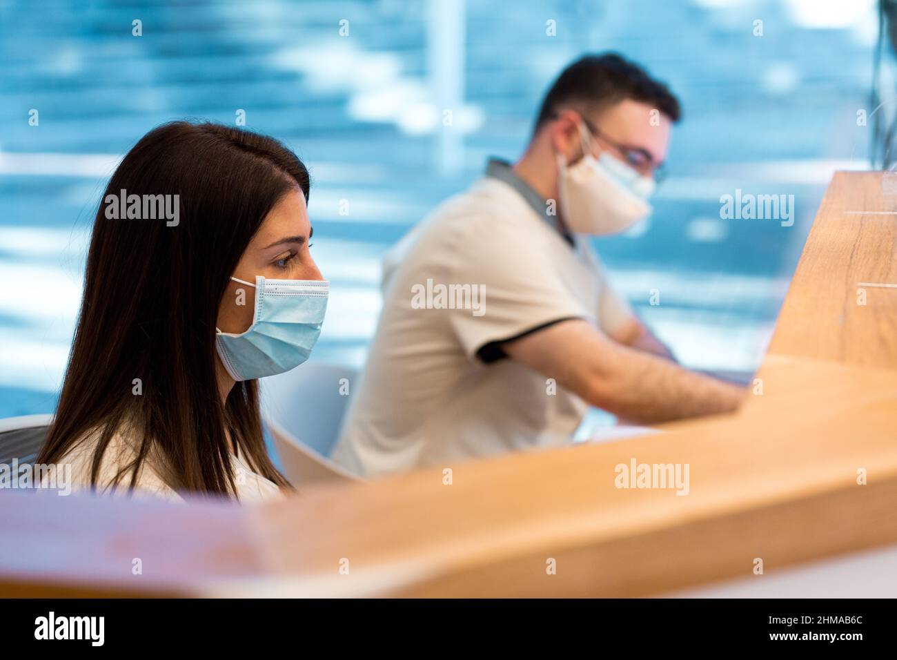 Zwei Personen trugen eine Gesichtsmaske, während sie an der Rezeption eines medizinischen Zentrums arbeiteten. Stockfoto
