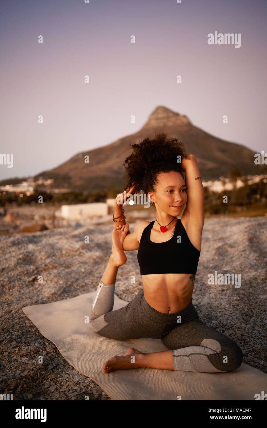 Shes hat eine Leidenschaft für Yoga. Ganzkörperaufnahme einer attraktiven jungen Frau, die am Strand bei Sonnenuntergang Yoga praktiziert. Stockfoto