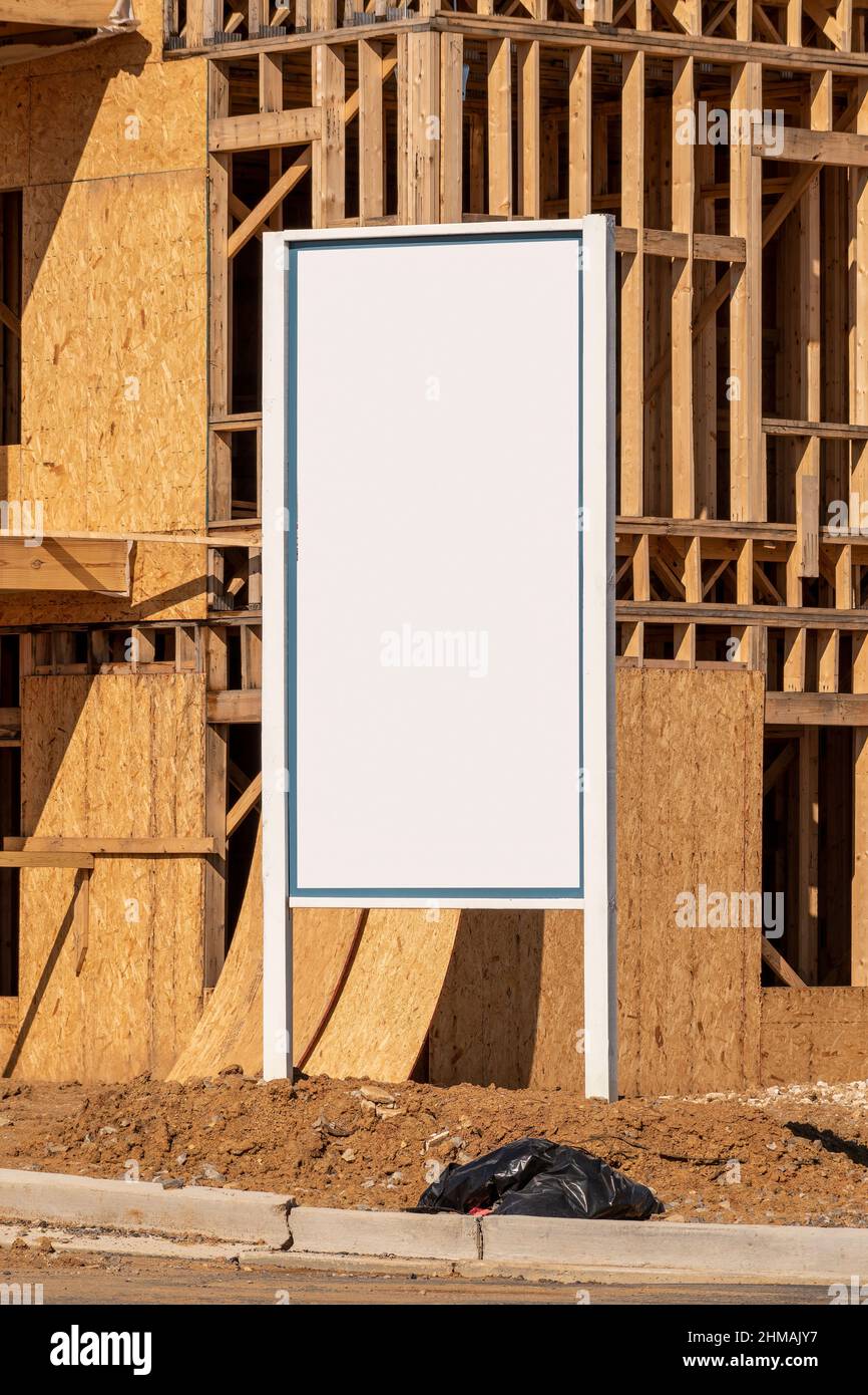 Vertikale Nahaufnahme eines weißen Schildes vor den im Bau befindlichen neuen Wohnungen. Stockfoto