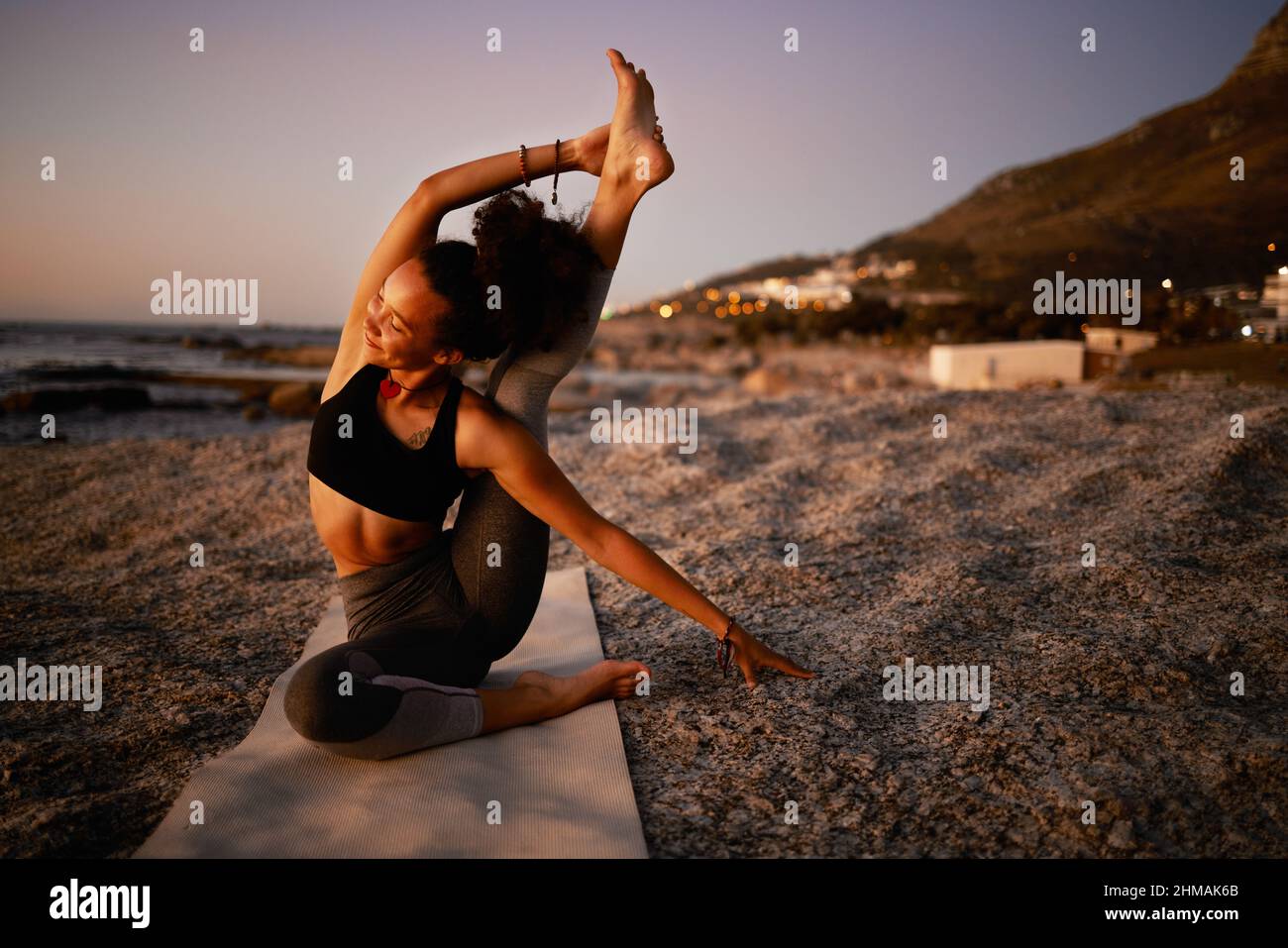 Yoga kann deine Seele heilen. Ganzkörperaufnahme einer attraktiven jungen Frau, die am Strand bei Sonnenuntergang Yoga praktiziert. Stockfoto