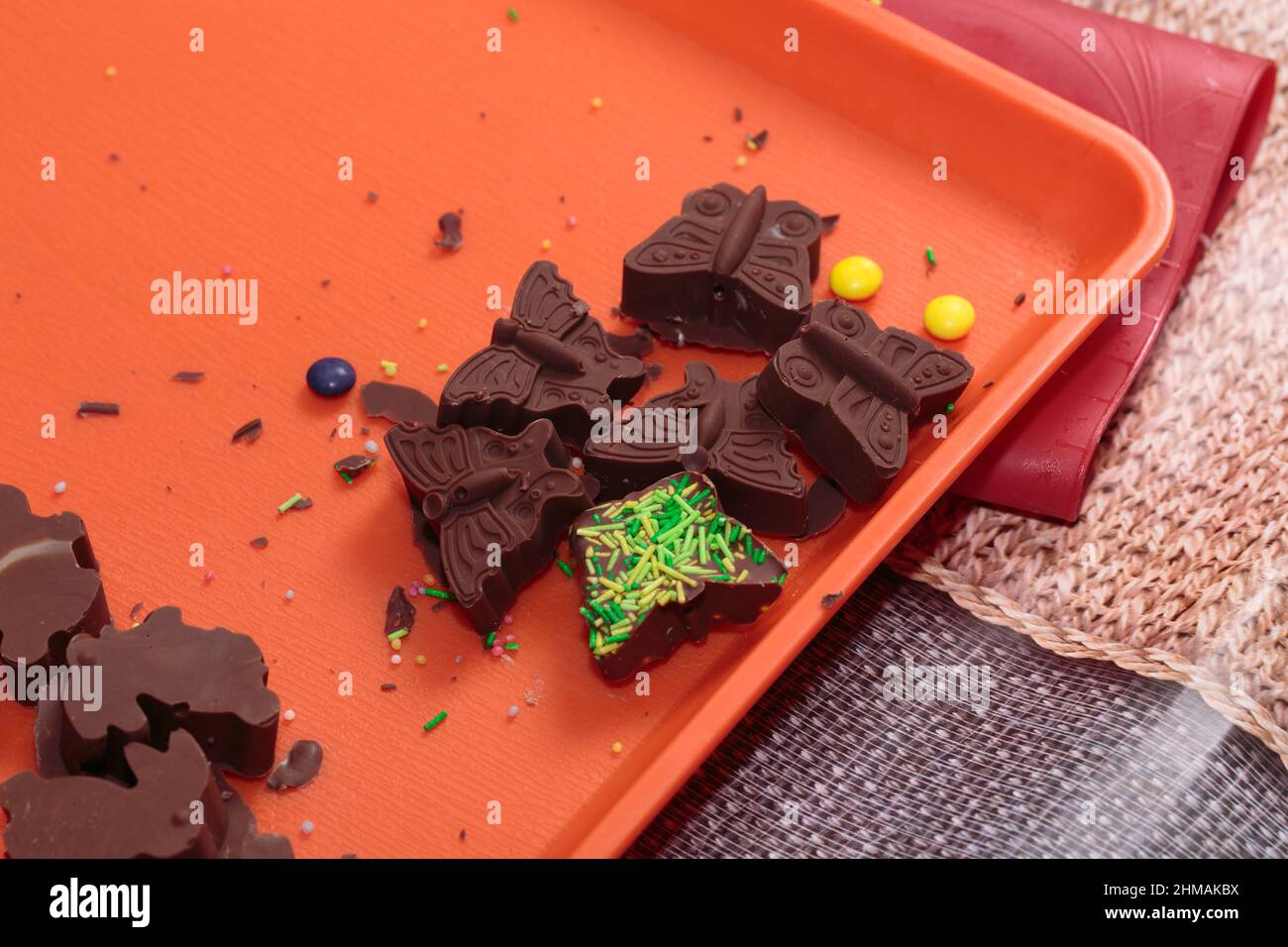 Schmetterlingsförmige dunkle Schokoladentafeln auf einem orangefarbenen Tablett. Es ist hausgemacht. Nahaufnahme. Stockfoto
