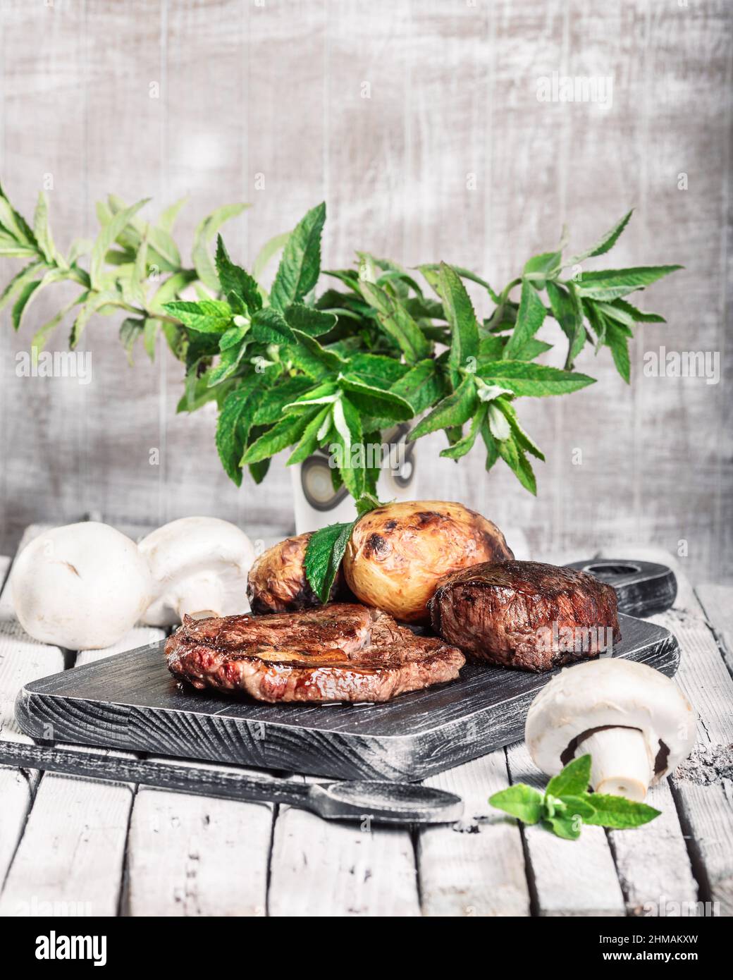 Auswahl an mittelseltenen Steaks, geschnitten mit Messer mit Kartoffelkeilen als Beilage. Kochen im Freien, und tolle Schnitte von Sirloin, Filet. Grill Stockfoto