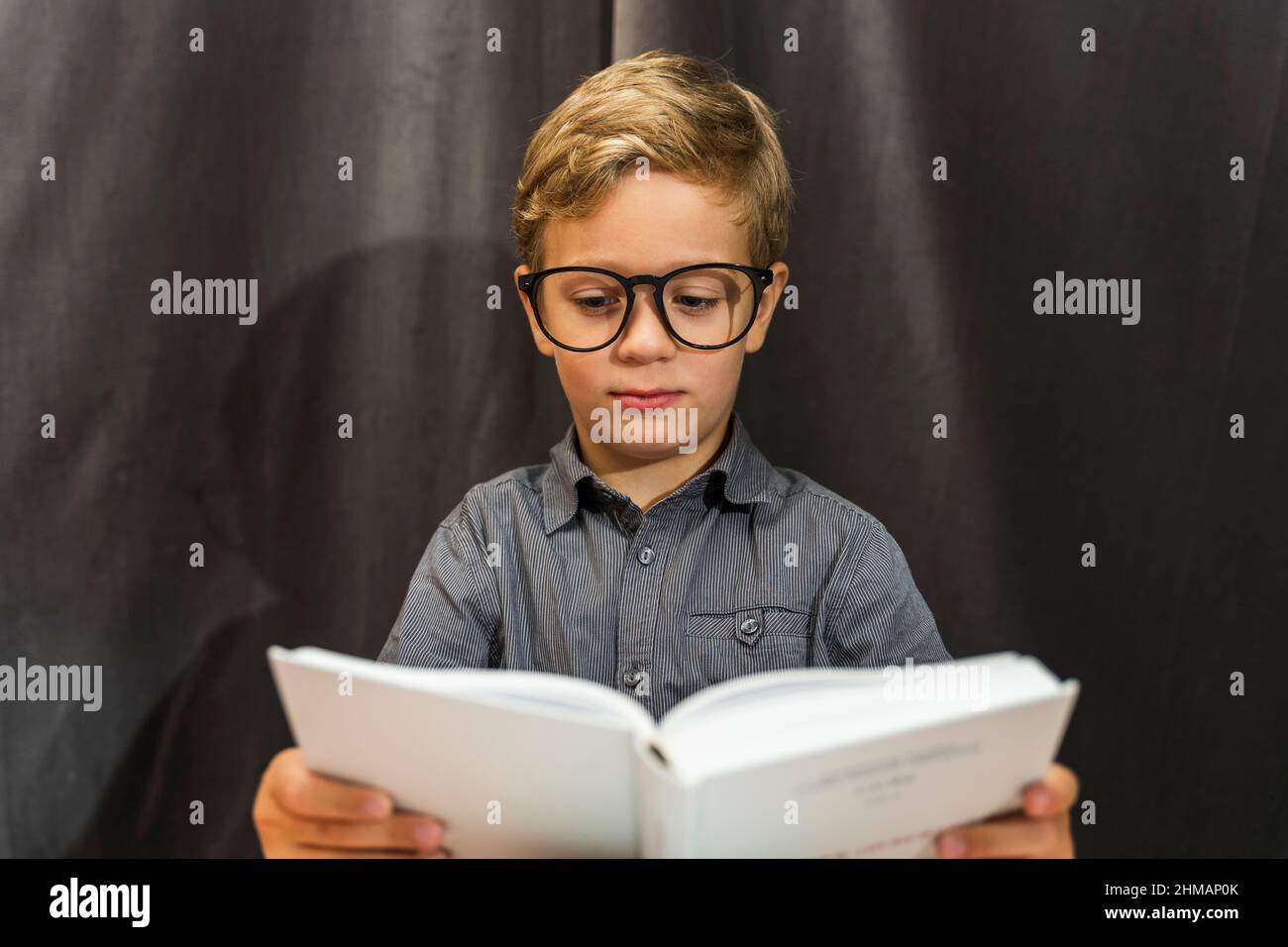 Junge liest ein Buch, Junge mit Brille, Bildung, zurück zur Schule, Lernschwierigkeiten. Stockfoto