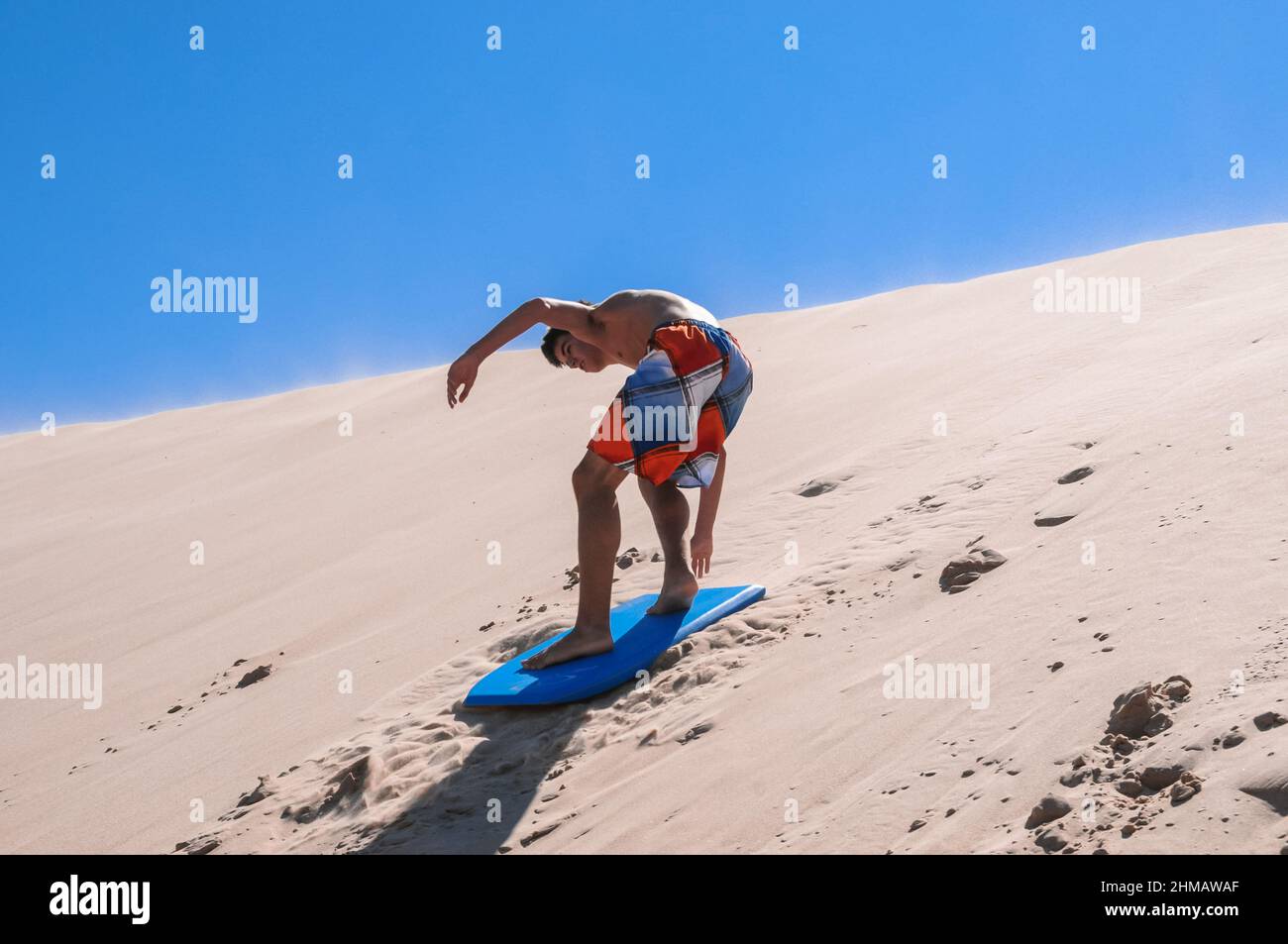 Kaukasischer junger Mann, der auf einem Brett im Sand der Dünen von Tarifa rutscht Stockfoto