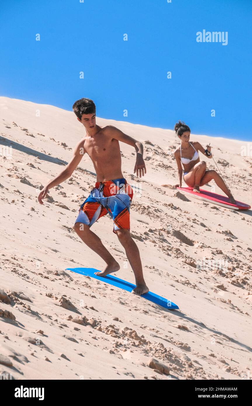 Kaukasische Jugendliche, die auf einem Brett im Sand der Dünen von Tarifa gleiten Stockfoto
