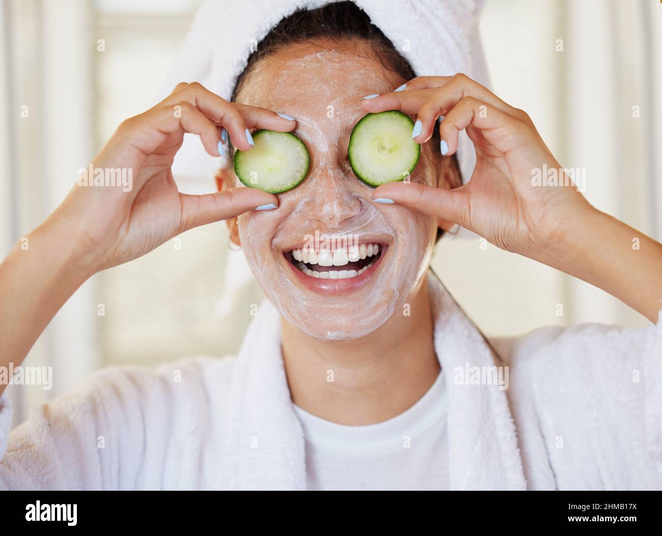 Ich brauchte einen Spa-Tag. Aufnahme einer schönen jungen Frau, die während ihrer Schönheitsroutine Gurken vor dem Auge hält. Stockfoto