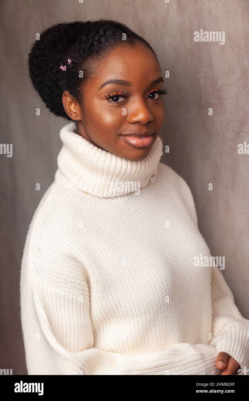 Eine schöne junge schwarze Frau, die einen weißen Rollkragenpullover trägt. Stockfoto