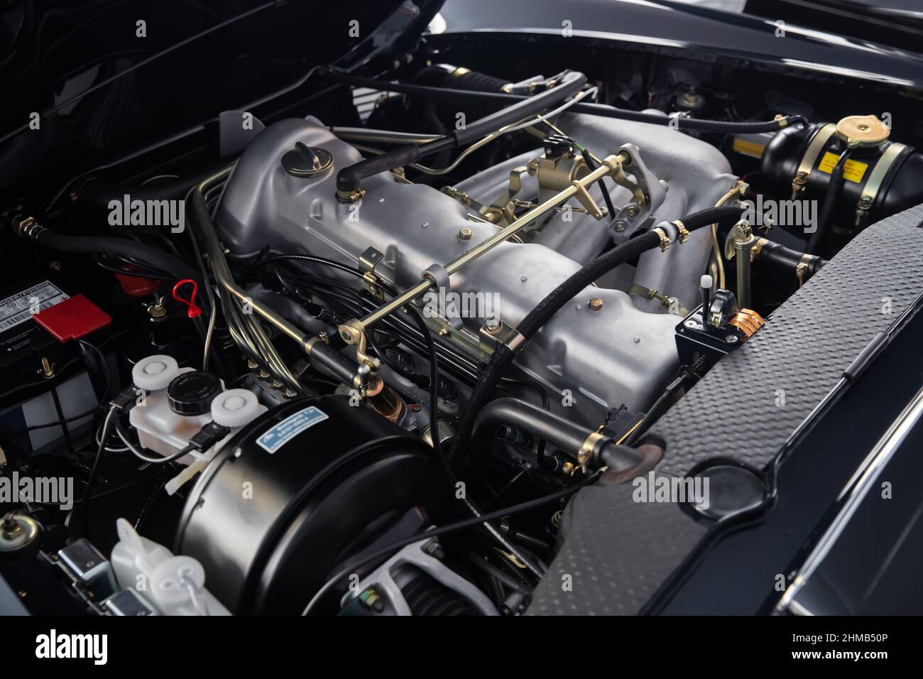 Schauen Sie unter die Motorhaube eines Retro-Autos in perfektem Zustand, sauberer Motor, viele Hebel, Schläuche und Drähte, Vintage Stockfoto