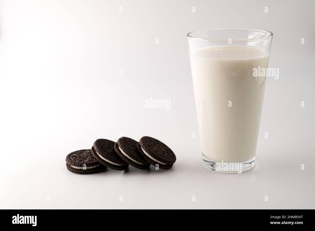 Eine Reihe von Schokoladencremesklätzchen neben einem Glas voller Milch auf einem isolierten weißen Hintergrund. Stockfoto